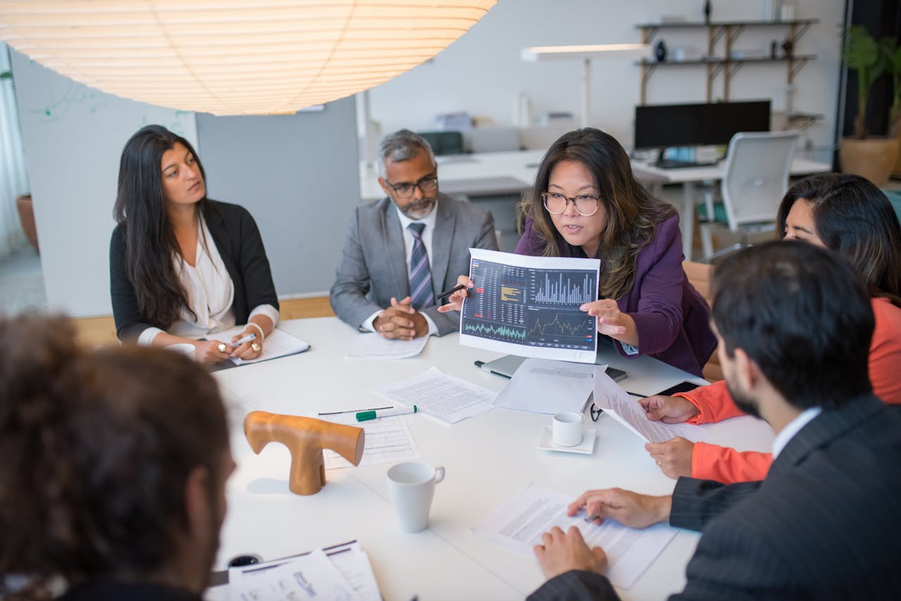 about-05 Multicultural team discussing analytics in a professional business meeting setting with data charts.